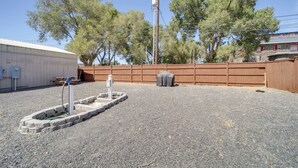 A gravel area with a concrete planter, a wooden fence, and a building in the background. - Private Patio, Steps to Lake: Soap Lake Studio! (Soap Lake)
