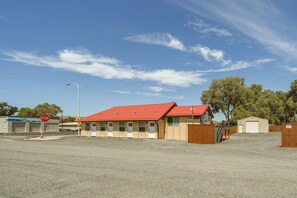 A building with a red roof, a garage, and a small shed.