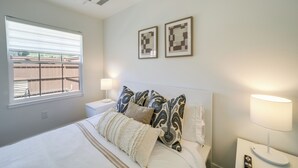 Une chambre à coucher avec un lit, deux lampes de chevet, une fenêtre et un climatiseur fixé au mur.