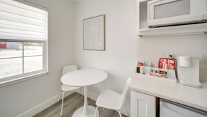 A small kitchenette with a microwave, coffee maker, and a coffee pod holder. There is a white table and two chairs. - Walk to Water: Soap Lake Studio w/ Patio! (Soap Lake)