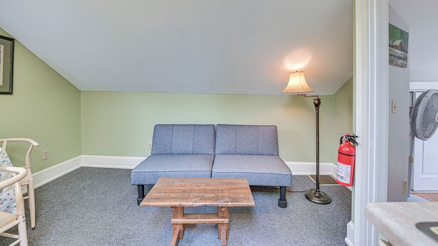 Une pièce avec un canapé gris, une table en bois, un lampadaire et un extincteur.