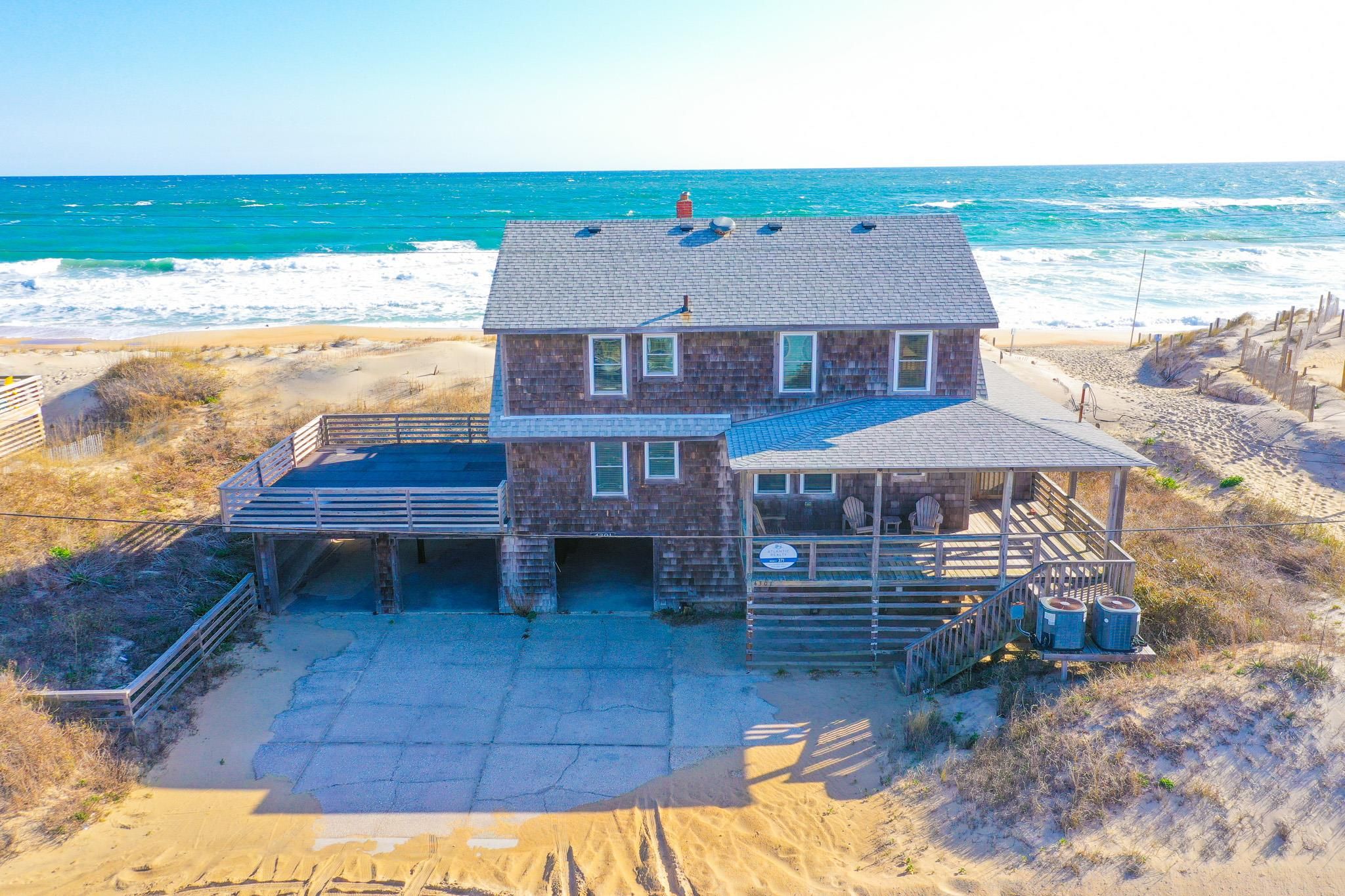 Une maison située en bord de mer, dotée d’un patio couvert, d’une piscine et offrant une vue sur l’océan.