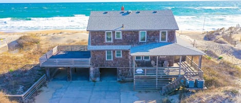 Une maison située en bord de mer, dotée d’un patio couvert, d’une piscine et offrant une vue sur l’océan.