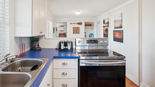 A modern kitchen with a stainless steel sink, a coffee maker, a toaster, and a stove.