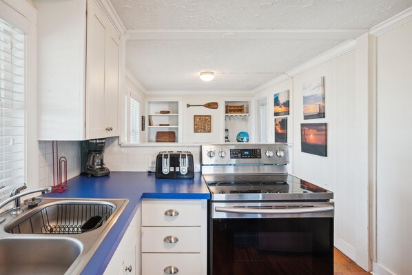 A modern kitchen with a stainless steel sink, a coffee maker, a toaster, and a stove.