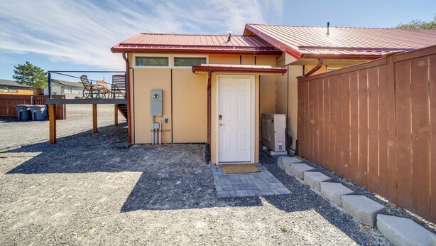 A small building with a red roof, a white door, and a wooden fence. - Steps to Soap Lake: Studio Stay w/ Patio! (Soap Lake)