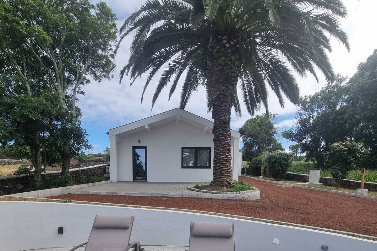 Una casa moderna con fachada blanca, un pequeño porche y dos sillones.