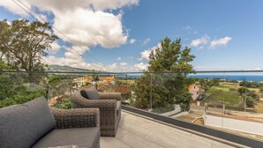 A balcony with wicker furniture and a view of the sea and landscape. - Ápice - by Azores Green Villas  (Ponta Delgada)