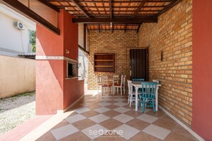 Une terrasse extérieure avec un mur en briques, un sol carrelé et un plafond en bois.