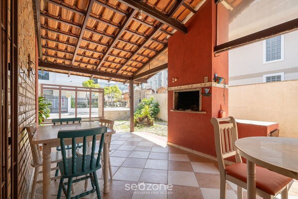 Une terrasse extérieure avec un sol carrelé, des meubles en bois et un mur en briques.