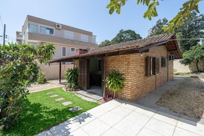Une petite maison en briques avec un toit en tuiles, une allée pavée et une pelouse bien entretenue.