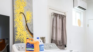 Une buanderie équipée d’un lave-linge, d’un sèche-linge et ornée d’un grand tableau au mur.