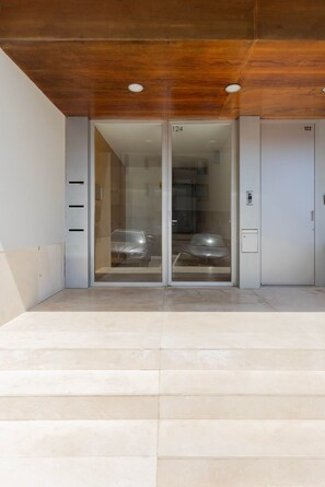 A modern building entrance with a glass door, a car parked inside, and a number 122 on the wall. - Liiiving in Porto - Foz Seaside Apartment (Porto)