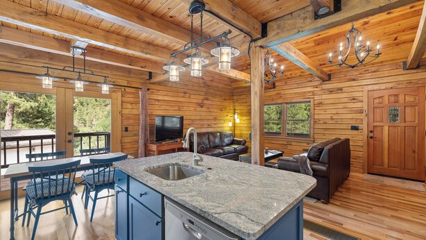 A wooden cabin interior with a kitchen, dining area, and living room. - Beautifully Renovated Property Just off Highway Close to Trails and Lead! (Lead)