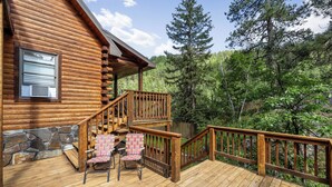 A wooden cabin with a deck, stone wall, and a staircase leading to a second level. - Beautifully Renovated Property Just off Highway Close to Trails and Lead! (Lead)