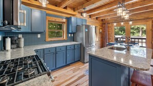 A modern kitchen with blue cabinets, a granite countertop, stainless steel appliances, and a wooden ceiling. - Beautifully Renovated Property Just off Highway Close to Trails and Lead! (Lead)