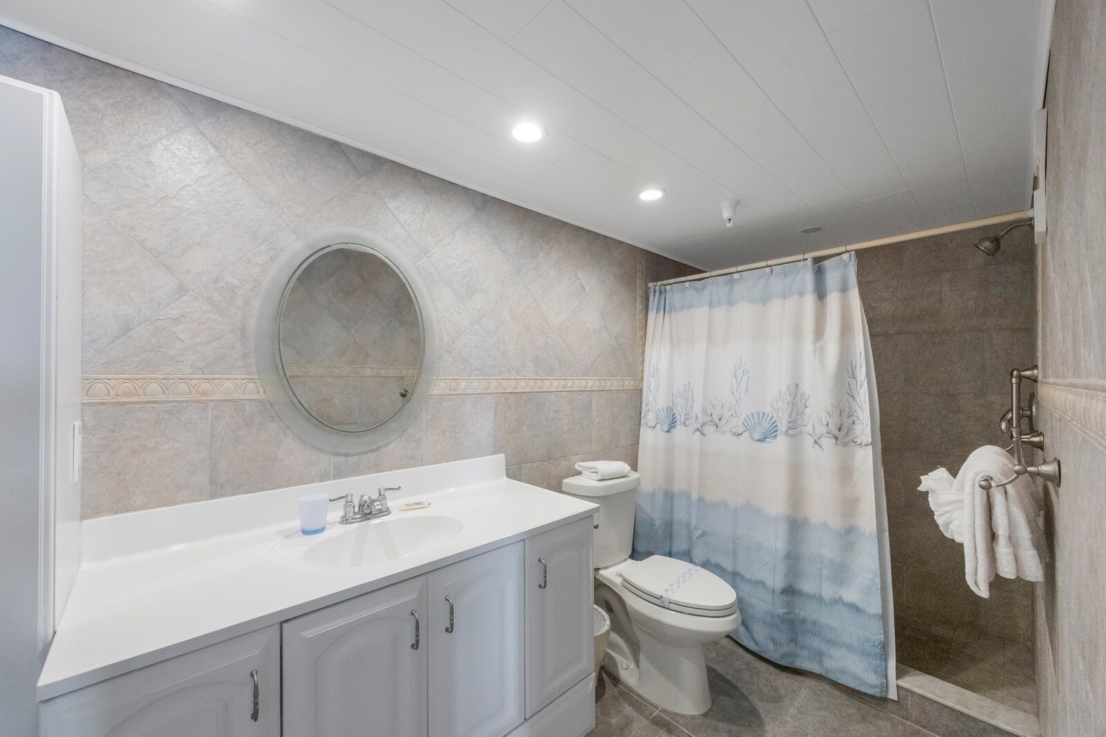A bathroom with a white sink, a toilet, and a shower area with a blue and white shower curtain.