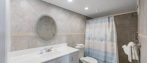 A bathroom with a white sink, a toilet, and a shower area with a blue and white shower curtain.