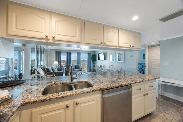 A modern kitchen with granite countertops, stainless steel appliances, and light-colored cabinetry. - Bright & Updated Beachfront Complex 2BR2BA (Madeira Beach)