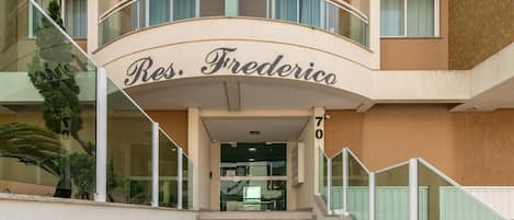Entrada de un hotel con un balcón curvo y el nombre "Res. Frederico" sobre las puertas.