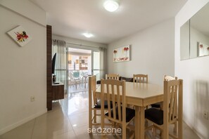 Un comedor con mesa y sillas de madera, un espejo grande y obras de arte en las paredes.
