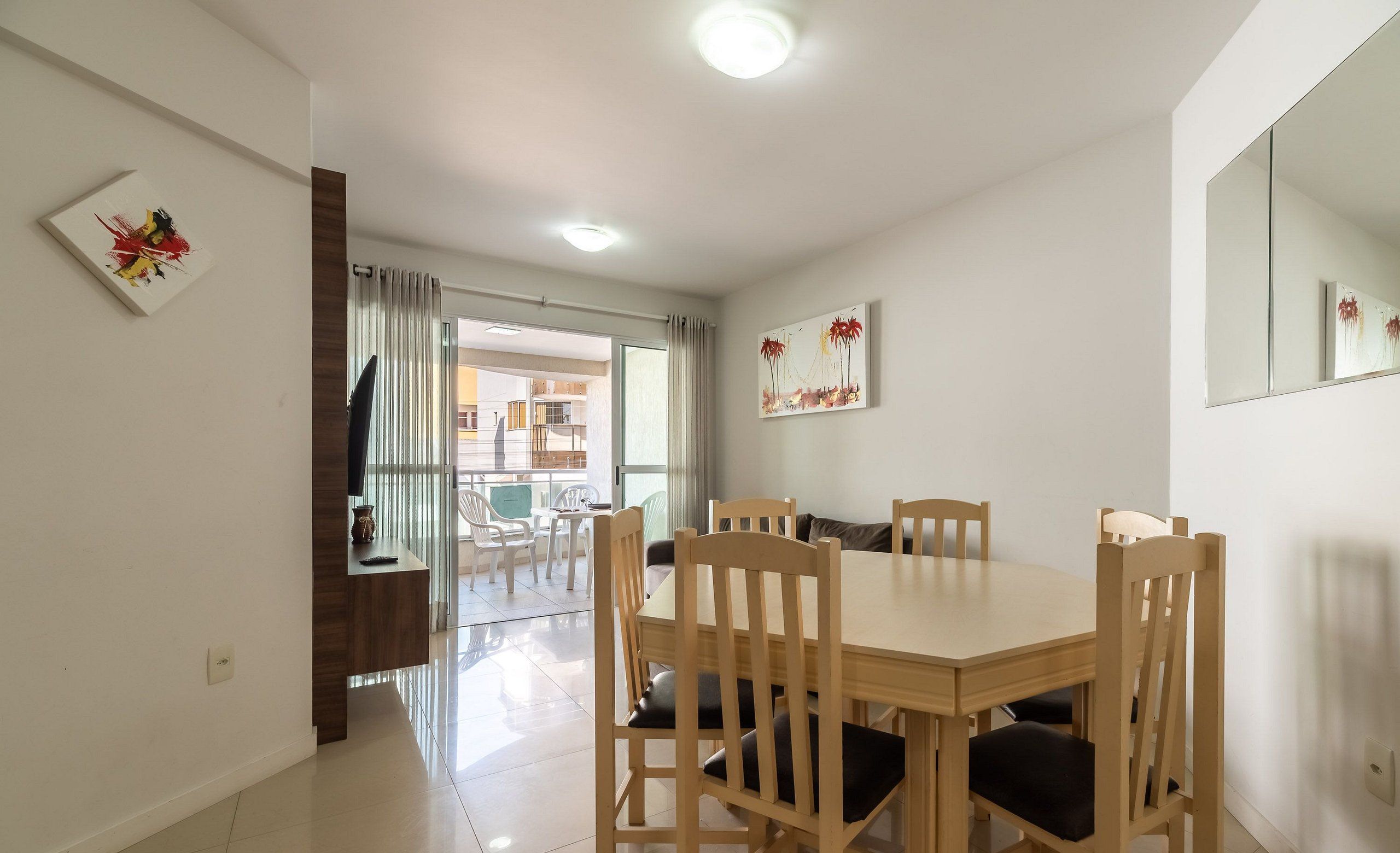 A dining area with a wooden table and chairs, a large mirror, and artwork on the walls.