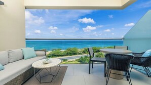 Ein Balkon mit einer Couch, Stühlen und einem Tisch mit Blick auf die Küste.