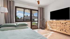 A bedroom with a bed, curtains, a ceiling fan, a TV, and a balcony with a view.