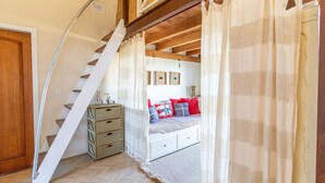 A bedroom with a bed, a staircase, and a small wooden chest of drawers. - Comfortable Duplex in Praia do Rosa - SC Rfe000 (Imbituba)