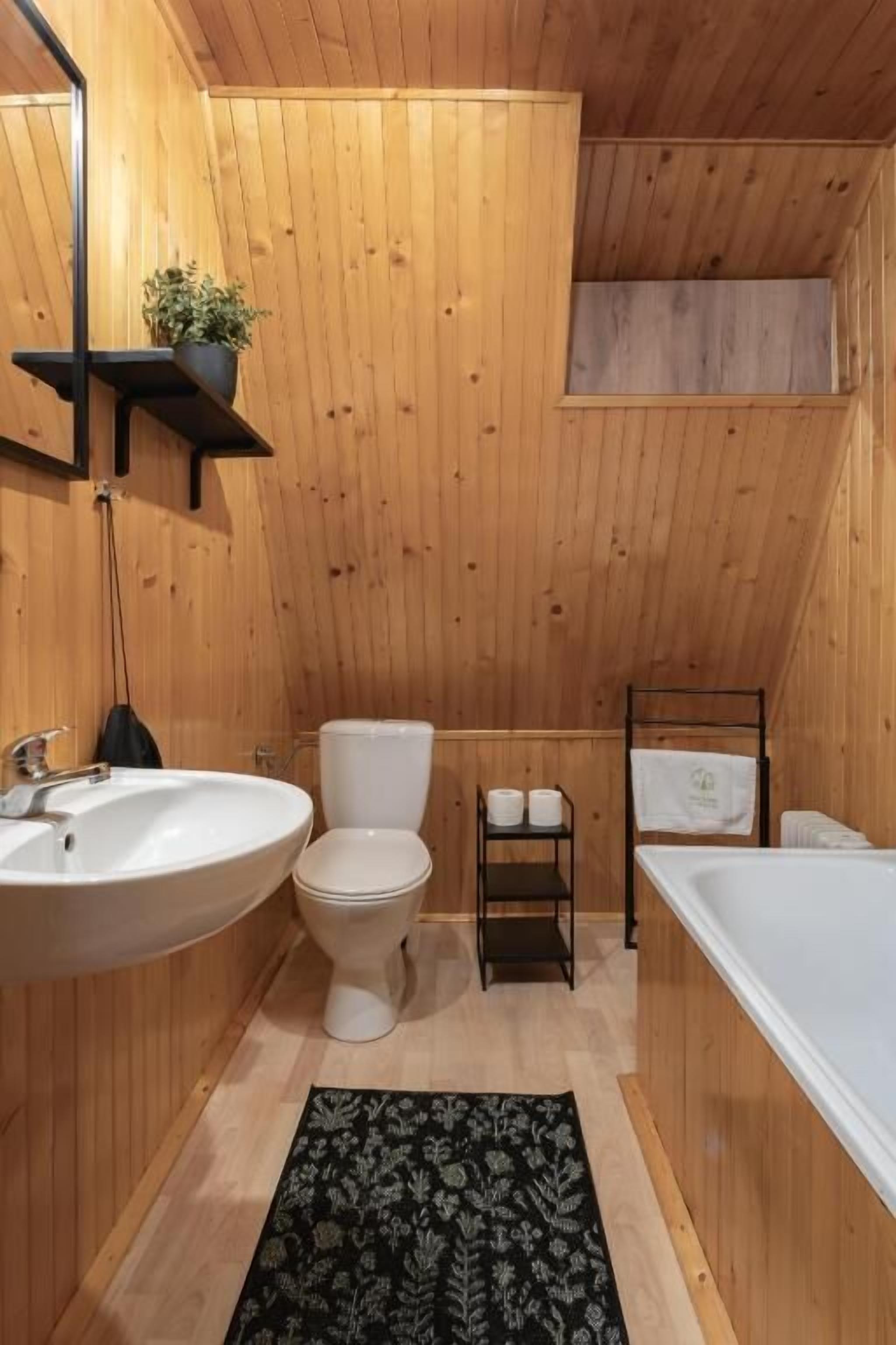 Un baño con paneles de madera, un lavabo, un inodoro y una bañera.