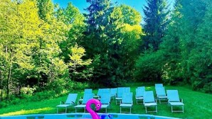 Una piscina con un flotador con forma de flamenco rosa y sillones de descanso al fondo.