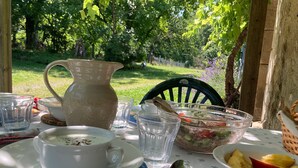 Ein Tisch im Freien mit einer Kanne, Schüsseln und Besteck.