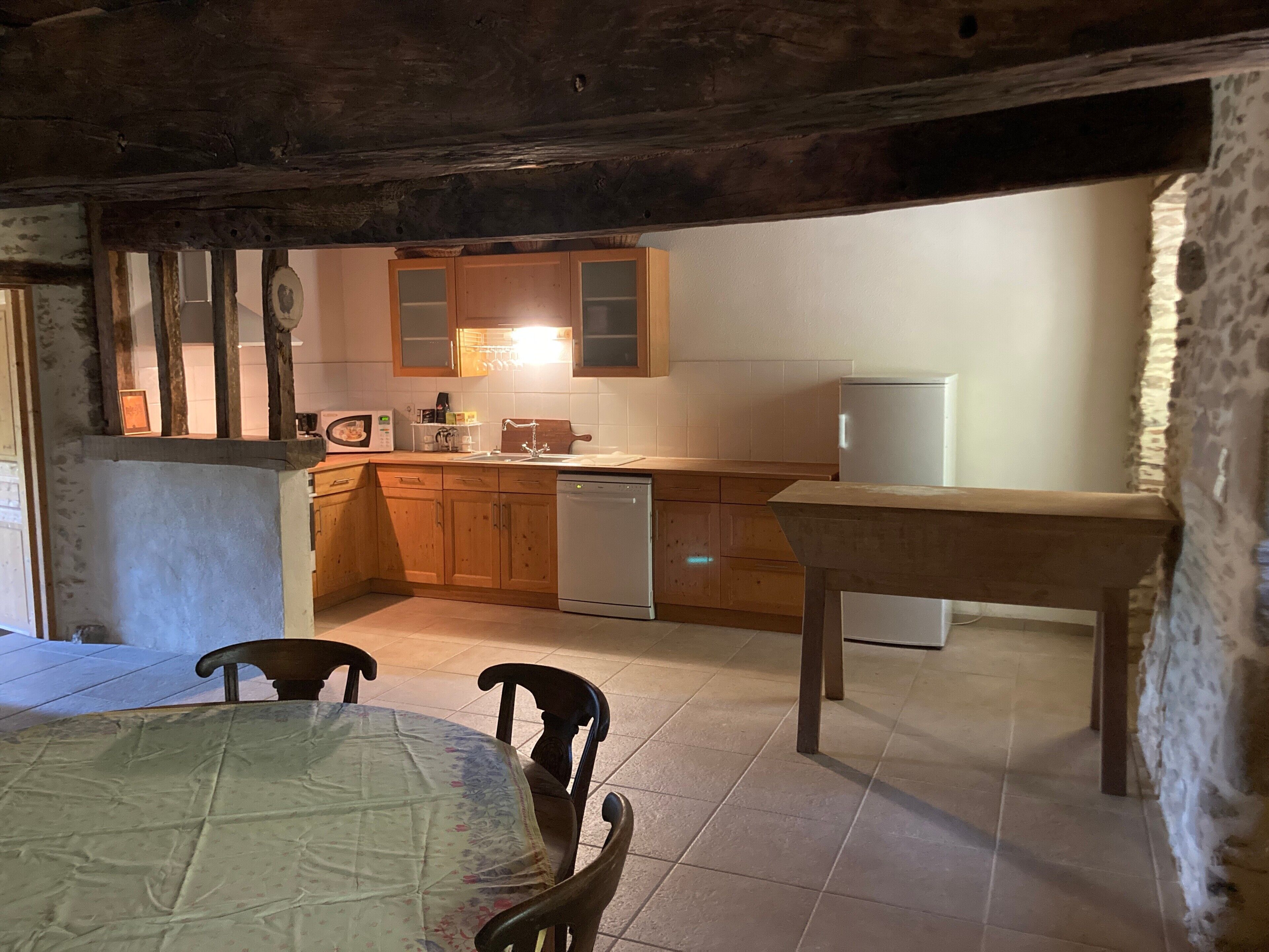 Une cuisine rustique avec des meubles en bois, un évier, un four à micro-ondes et un coin repas comprenant une table et des chaises.