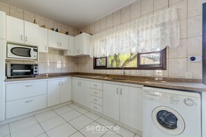 A kitchen with white cabinets, a microwave, a toaster, a sink, and a washing machine. - 3BR Home w/ BBQ 140m From the Beach Rae0126 (Bombinhas)