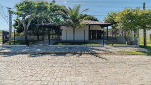 A paved driveway leading to a gated property with a covered patio, surrounded by trees and a fence. - 3BR Home w/ BBQ 140m From the Beach Rae0126 (Bombinhas)