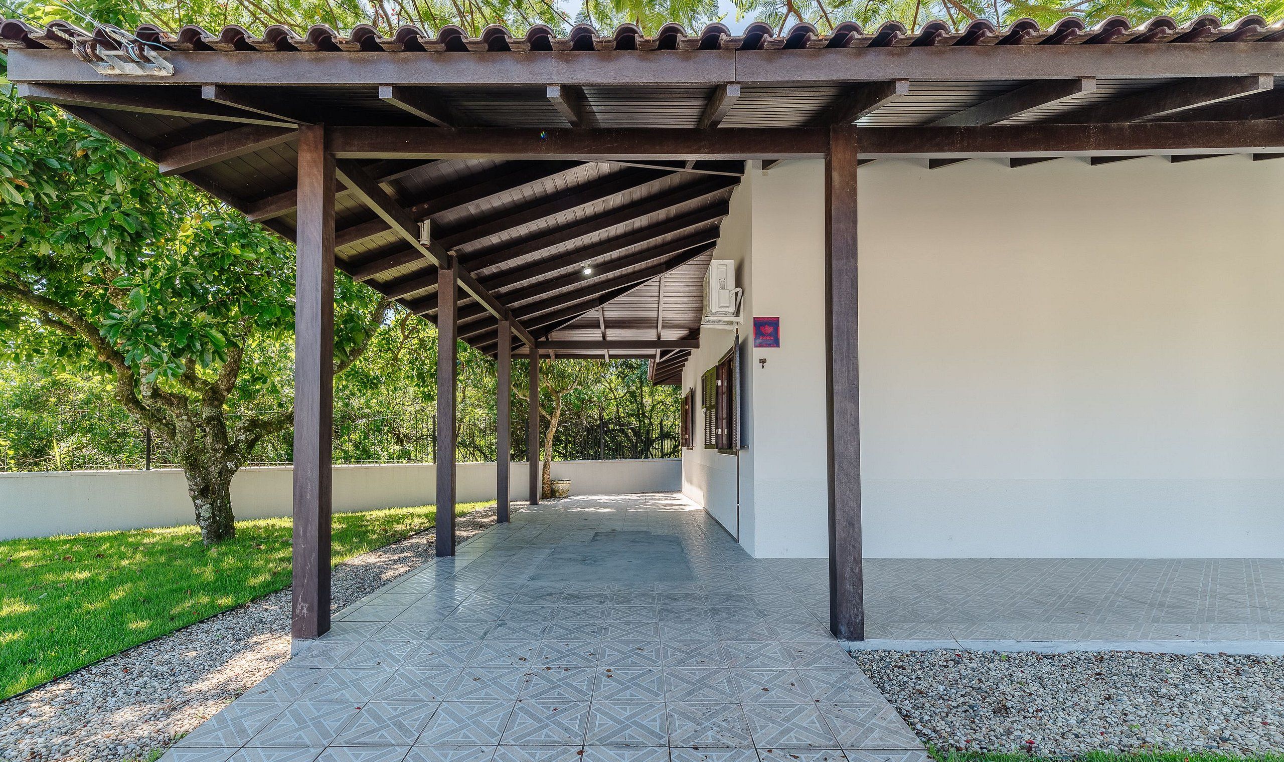 A covered outdoor area with a tiled floor, wooden pillars, and a tiled roof.