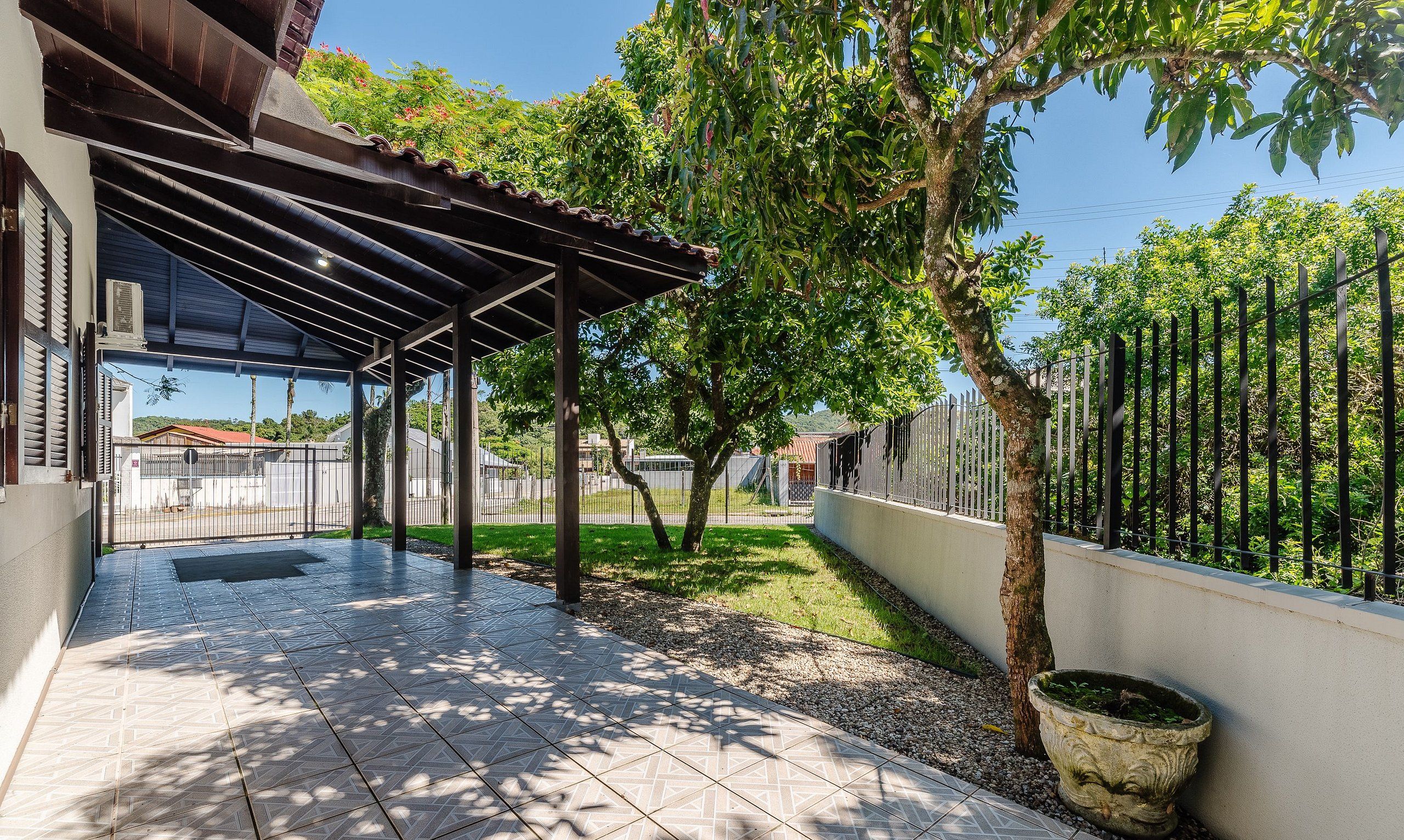 Un espace extérieur abrité, doté d’un sol carrelé, d’une pergola et d’un arbre.