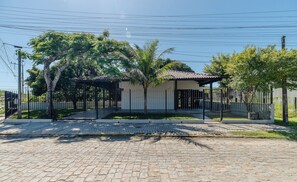 Un vialetto lastricato conduce a una proprietà recintata con un portico coperto, circondata da alberi e da una staccionata.