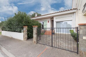 Une maison avec une entrée sécurisée par un portail, un garage et un mur en pierre.
