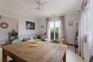 Un coin repas avec une table en bois, des paniers en osier et des chaises vertes.