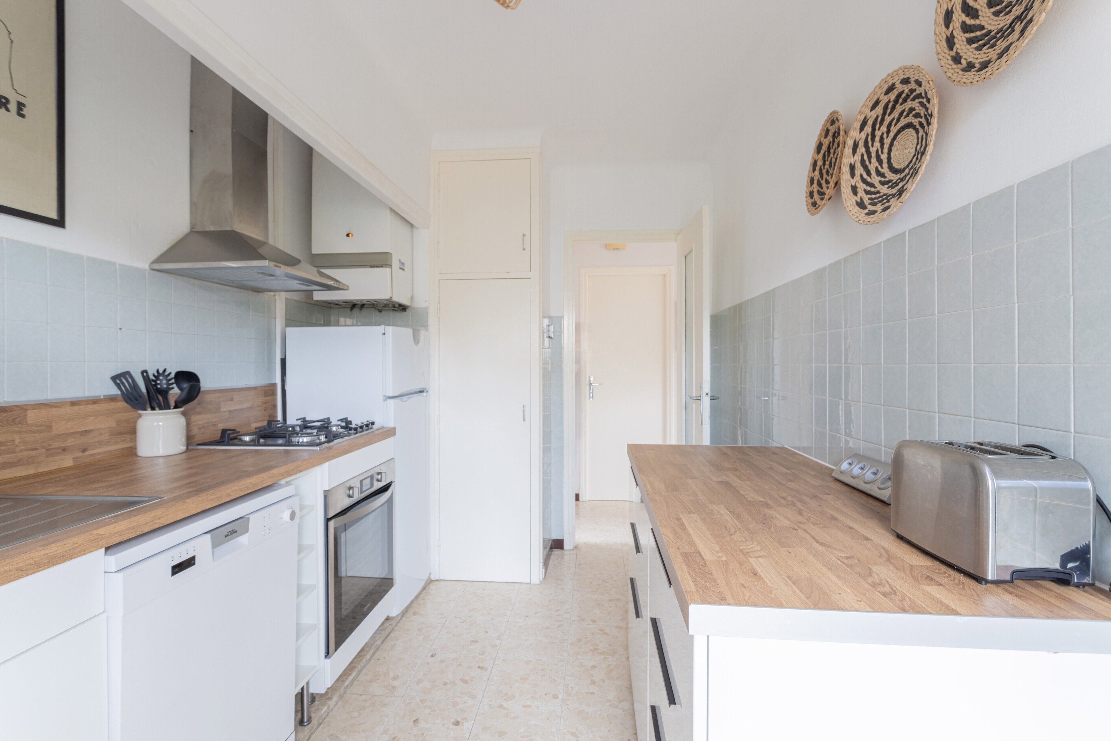 A kitchen with white cabinetry, a wooden countertop, a gas stove, a toaster, and a dishwasher.