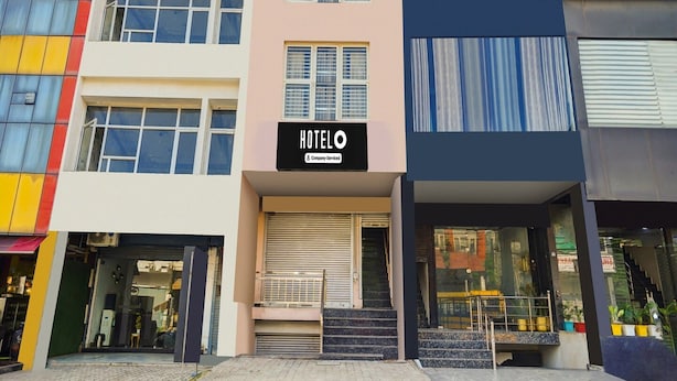 A multi-story hotel building with a sign reading 'HOTEL' and a company service logo. - Hotel O Green City Dhakoli Formerly Swagat (Dera Bassi)