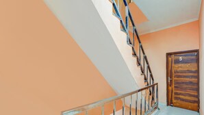 A staircase with a metal railing, a wooden door with the number 5, and a plain wall. - Hotel O Green City Dhakoli Formerly Swagat (Dera Bassi)