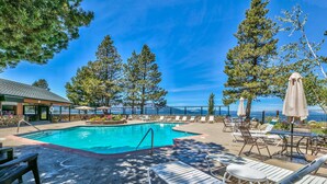 A swimming pool with lounge chairs and umbrellas, surrounded by trees and overlooking a scenic view. - 439AW Tahoe Keys Studio Perfect Couples Get Away (South Lake Tahoe)