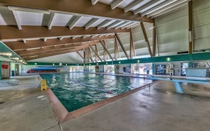 Une piscine intérieure avec un plafond haut, des couloirs de nage bien délimités et un poste de surveillance pour le sauveteur.