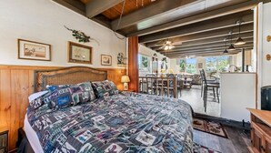 Un dormitorio con una cama grande, cabecera de madera y vistas a un comedor.