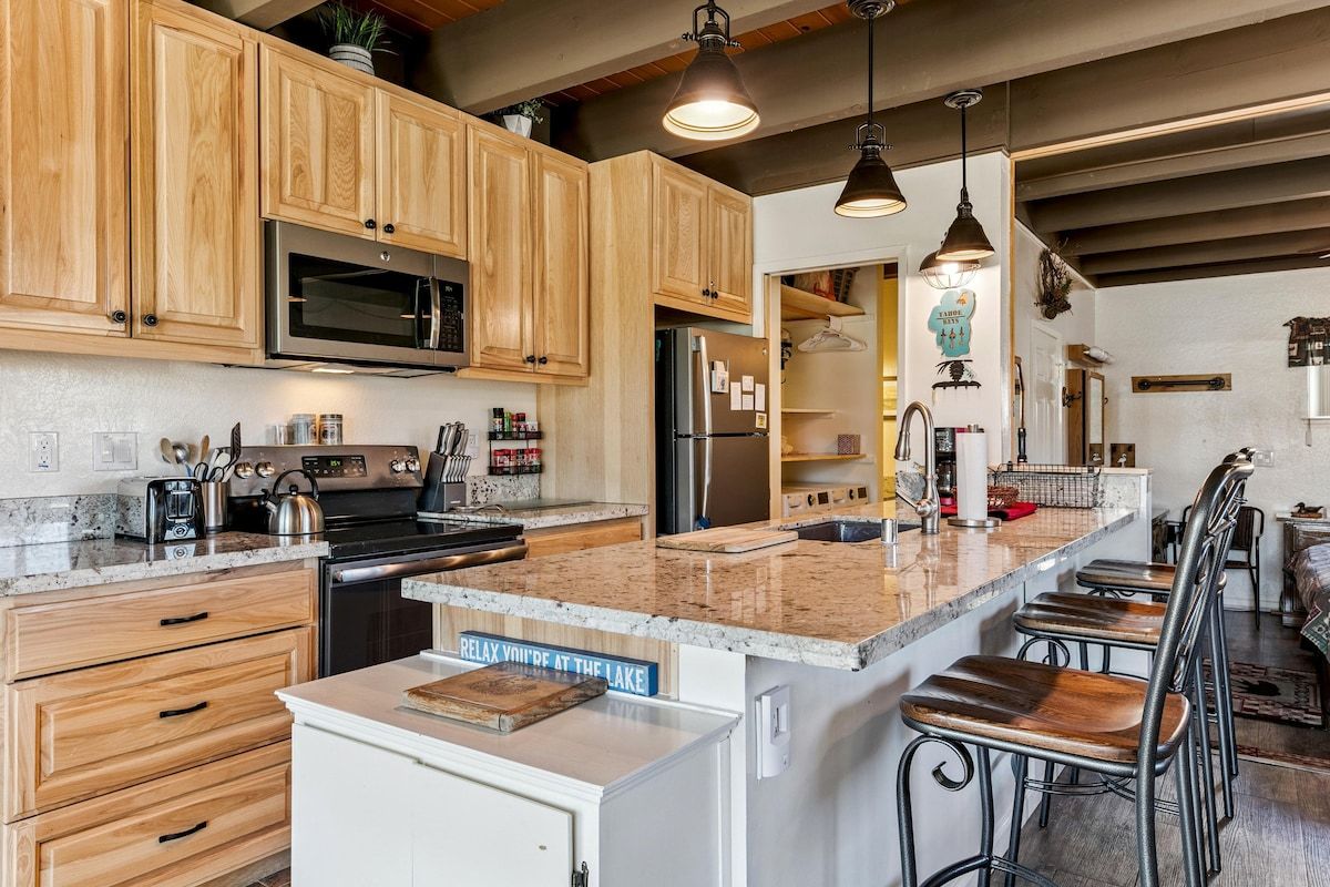 Una cocina con armarios de madera, electrodomésticos de acero inoxidable y encimera de granito.