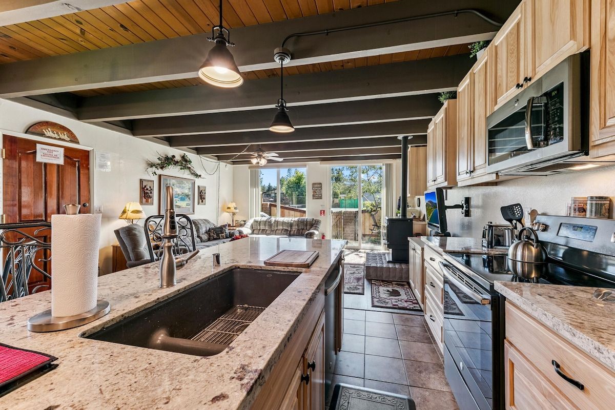 A modern kitchen with a large island, stainless steel appliances, and wooden cabinetry.