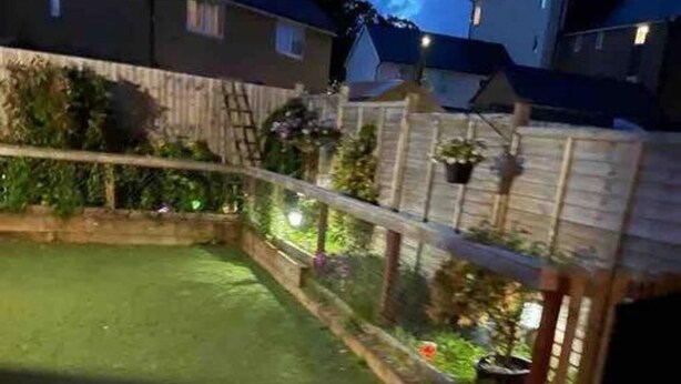 A residential backyard with a paved patio, a small pool, and a wooden fence.