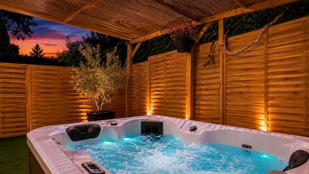 Un jacuzzi con una terraza de madera y una valla de madera al fondo.